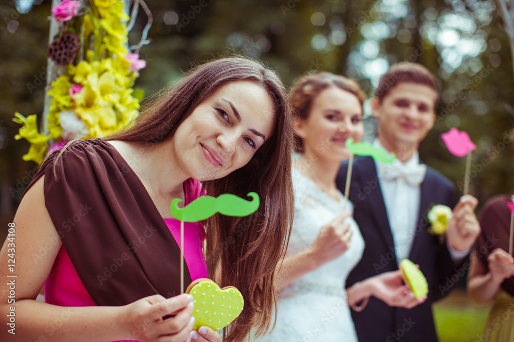 Fototapeta premium Bridesmaid in pink dress holds green paper moustache