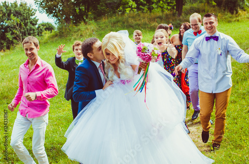 Groom catches bride and kissed her cheek while they walk with fr © pyrozenko13