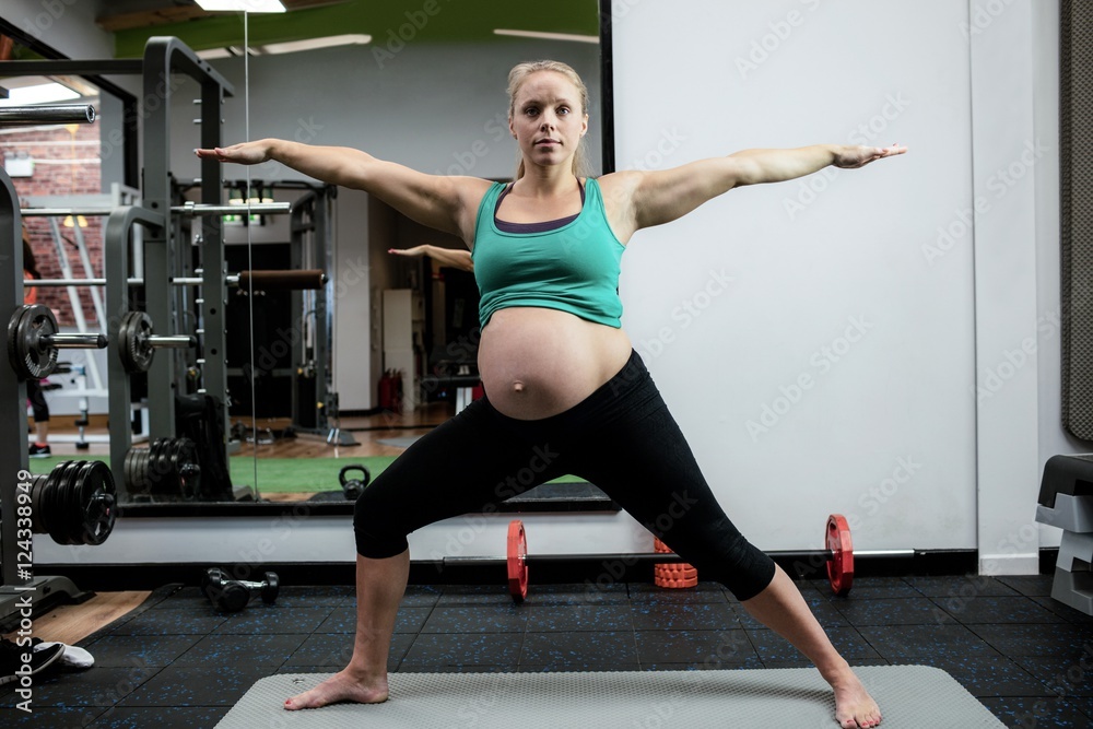 Pregnant woman performing stretching exercise on exercise mat Pregnant woman performing stretching exercise on exercise mat