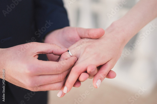 closeup of a groom putting a wedding ring onto the bride's finger during the ceremony