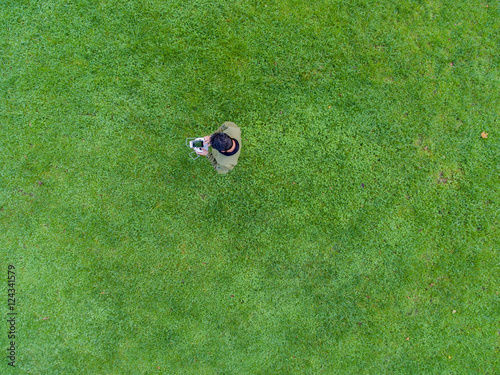 Mann auf grüner Wiese lenkt Drohne mit Fernsteuerung