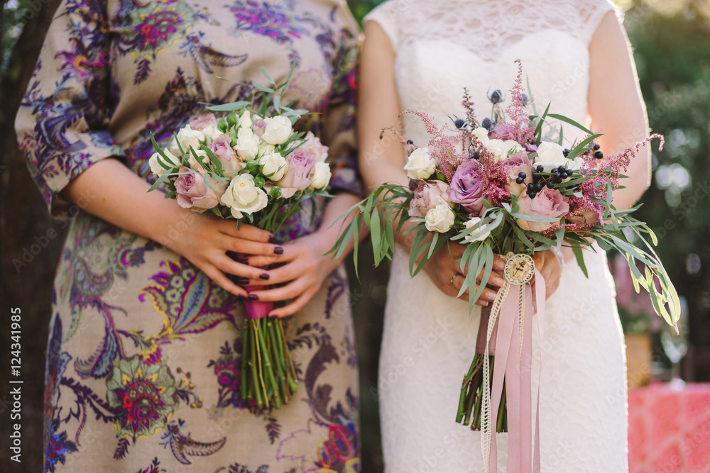bride and bridesmaid hold bouquets of white and purple flowers with heather bride and bridesmaid hold bouquets of white and purple flowers with heather
