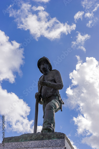 Firefighter statue with blue sky and clouds in the background
