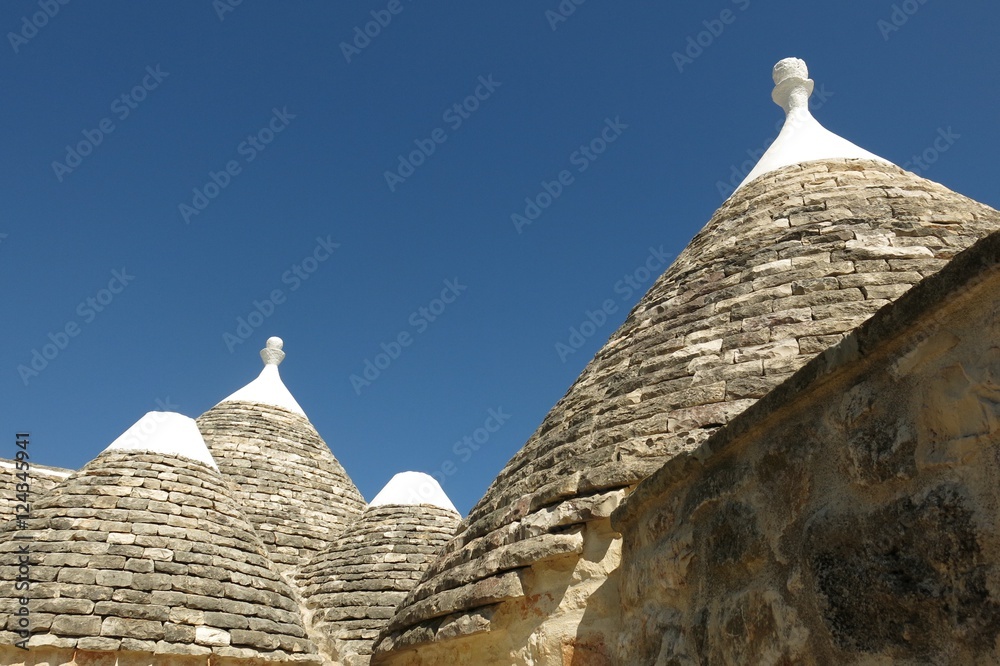 Trulli, the plural of trullo, in Apulia, Italy. These unusual stone structures have conical rooftops and are specific to the Itria Valley. 
