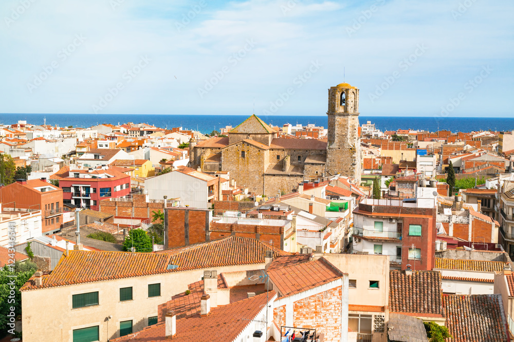 View over the roofs of old town Malgrat de Mar (Spain) from the hill with Mediterranean sea in the background and the Cathedral of the Coast in the middle