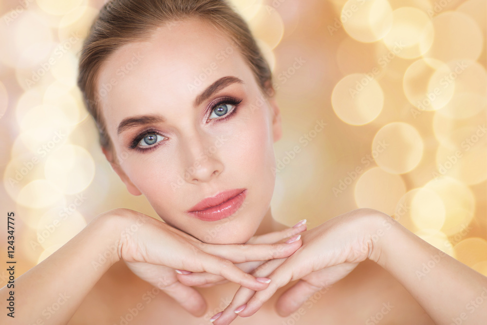 Naklejka premium beautiful young woman face and hands over lights