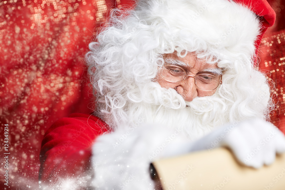Checking his special list. Traditional Santa Claus sitting at hi Checking his special list. Traditional Santa Claus sitting at hi