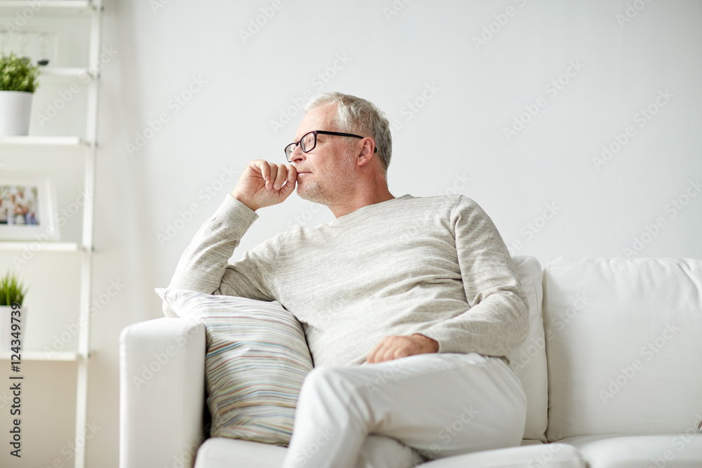  senior man sitting on sofa at home and thinking