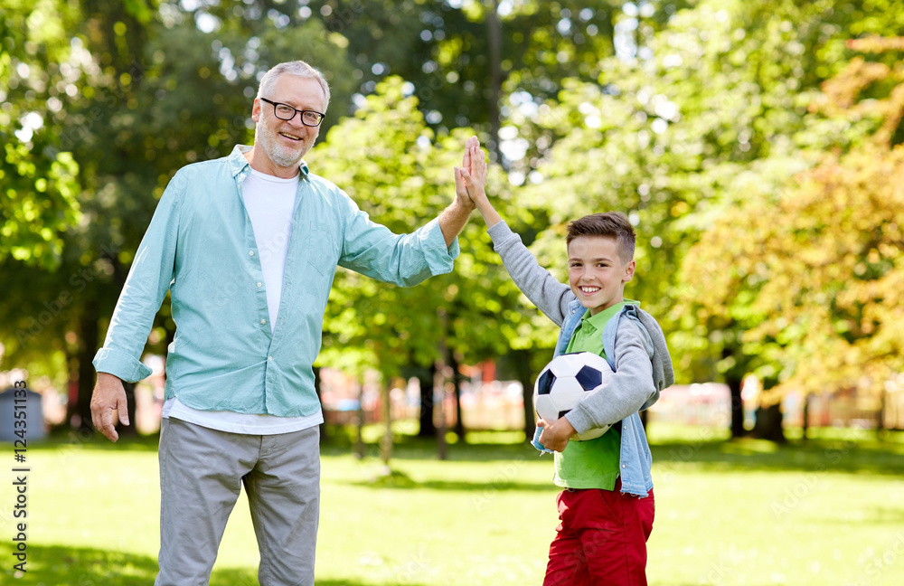 old man and boy with soccer ball making high five old man and boy with soccer ball making high five