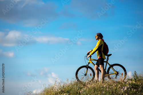 Cyclist riding a bike on off road to the sunset