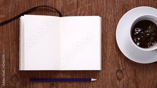 high-angle shot of a blank notebook, a pencil and a cup being filled with coffee on a rustic wooden table