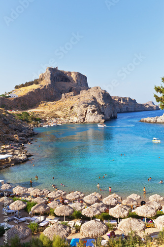 The sandy beach of St. Pauls Bay with clear blue water - a favorite place of rest in the town of Lindos, Rhodes