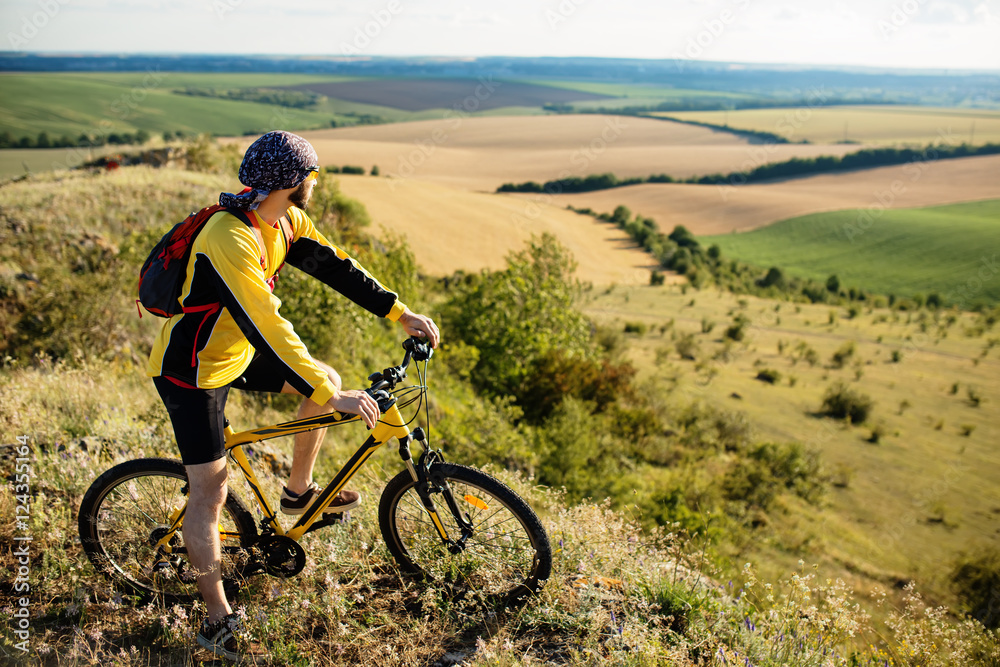 Cyclist riding a bike on off road to the sunset