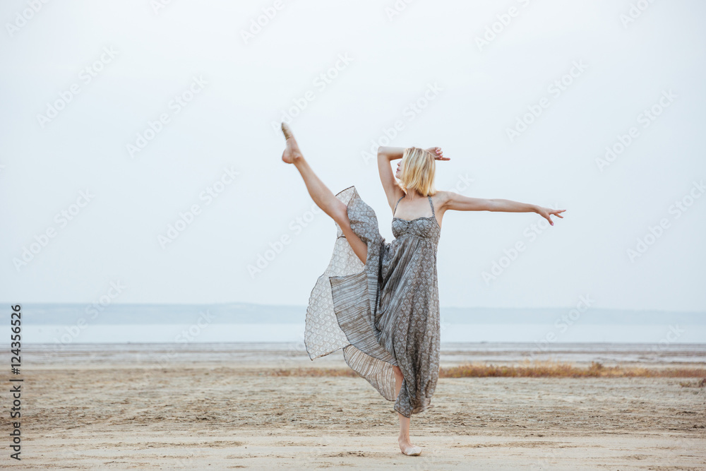 Graceful young woman dancer dancing on the beach Graceful young woman dancer dancing on the beach