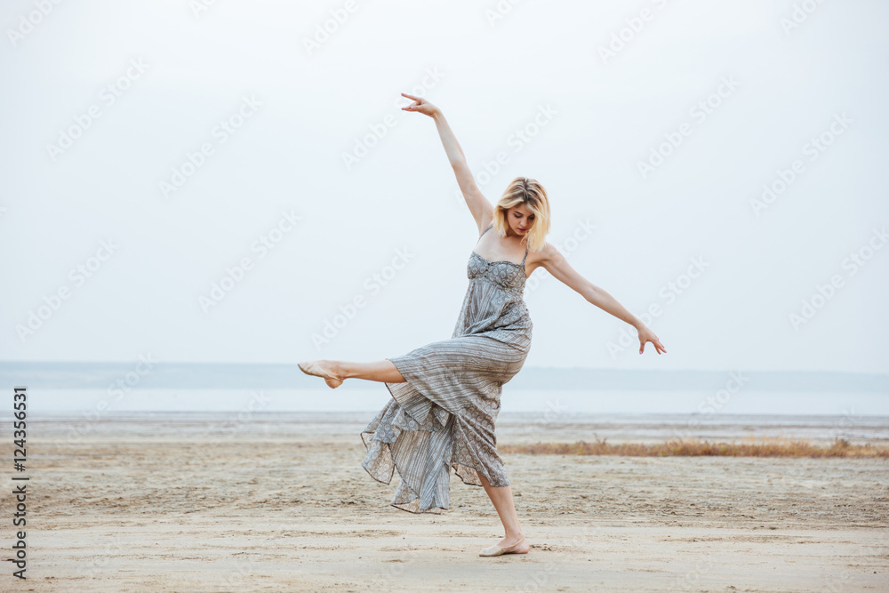 Woman dancer in long dress dancing barefoot on the beach Woman dancer in long dress dancing barefoot on the beach