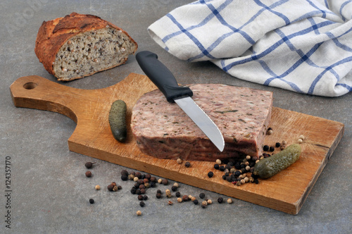 Pâté de campagne sur une planche à découper avec du pain, des cornichons et un mélange de baies photo