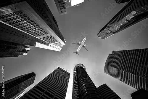 Tall city buildings and a plane flying overhead, Black and White tone #124358974