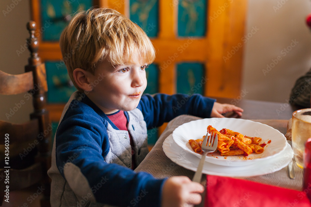 Blond child eats tomato pasta dish for lunch with family on Christmas Day Blond child eats tomato pasta dish for lunch with family on Christmas Day