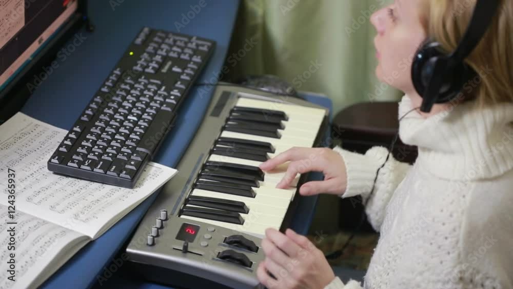 woman writes music on the computer. digital piano midi keyboard