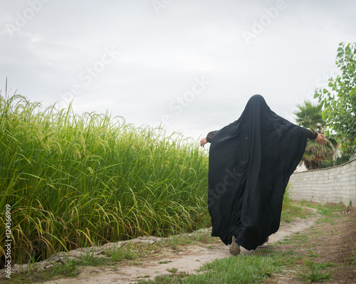 Beautiful happy Muslim woman in green field