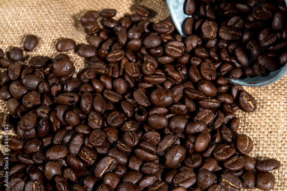 Arabica coffee beans in small tank on sack backgrounds