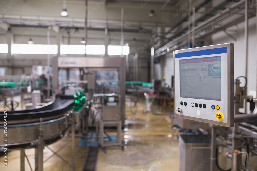 Industrial factory indoors and machinery. Robotic factory line for processing and bottling of pure spring water into canisters and bottles. Selective focus. Short depth of field.