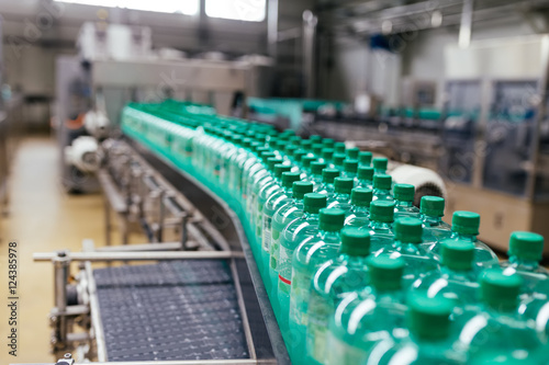 Industrial factory indoors and machinery. Robotic factory line for processing and bottling of pure spring water into canisters and bottles. Selective focus. Short depth of field.