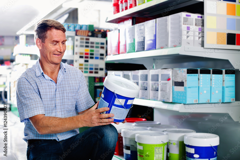 Portrait of male customer selecting paint can in housewares depa
