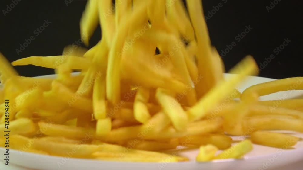 Pouring golden french fries on the plate. Popular fast food, deep fried potato chips. Super slow motion video