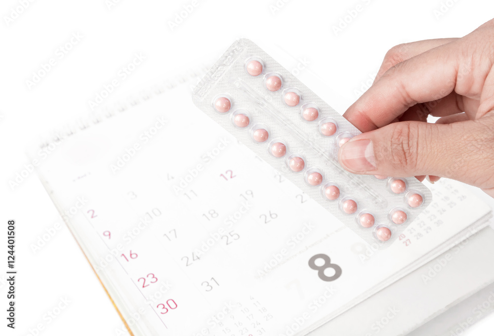 Close up hand hold birth-control pill with date of calendar back Close up hand hold birth-control pill with date of calendar back