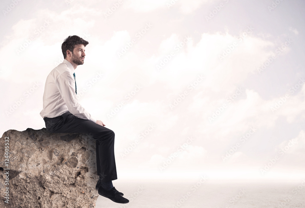 Business man sitting on stone edge Business man sitting on stone edge