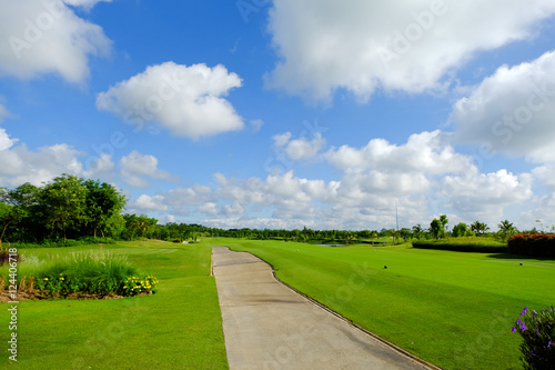 landscape view of concrete footpath with blue sky and white clouds background in golf course