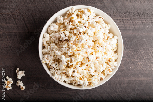 Olive oil popped popcorn in a porcelain bowl top view on a dark wooden background