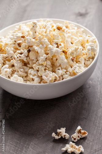 Olive oil popped popcorn in a porcelain bowl on a wooden background