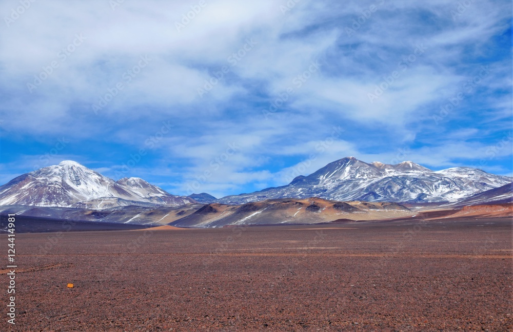 Long shot of the landscape surrounding Laguna Verde with snow captured mountains, brown hills and volcanic stones and rocks in Chile, South America
