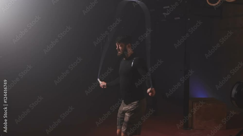 Strong sportsman with beard in black t-shirt doing jumping rope exercise. Strong sportsman with beard in black t-shirt doing jumping rope exercise.