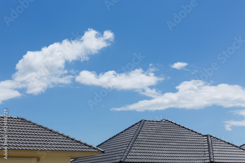 black tile roof on house with clear blue sky and cloud