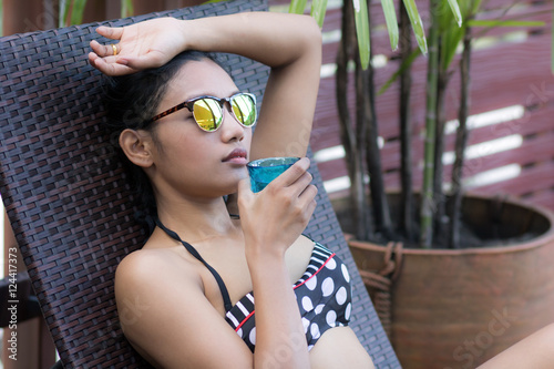 Woman with drink sunbathing on lounger photo