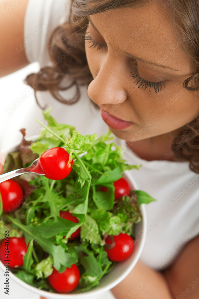 Youg woman eating healthy salad with lettuce and cherry tomatoes Youg woman eating healthy salad with lettuce and cherry tomatoes