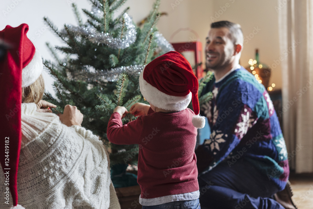 Obraz premium happy family with a young child decorating a christmas tree at h