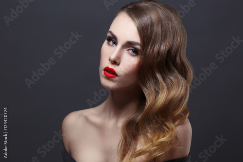 Fashion beauty portrait of gorgeous girl with curls and red lipstick in the style of Hollywood on a black background