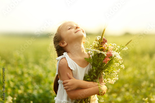 Happy little girl with flowers in the field photo