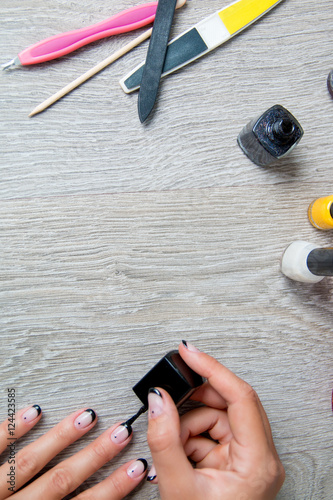 Black nail polish being applied to hand with tools for manicure on background. Beautiful  process.  Top view. Copy space. Frame. photo