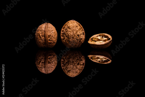 Two whole and one halved walnuts on black background photo