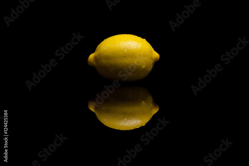 One whole isolated yellow lemon on black background