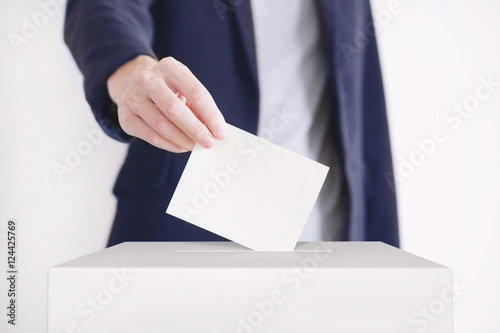 Voting. Man putting a ballot into a voting box. photo