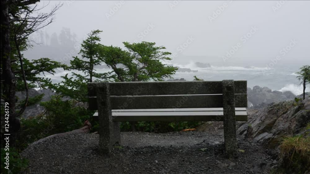 A bench overlooks a stormy ocean shoreline with waves crashing on black rocks.4k. A bench overlooks a stormy ocean shoreline with waves crashing on black rocks.4k.