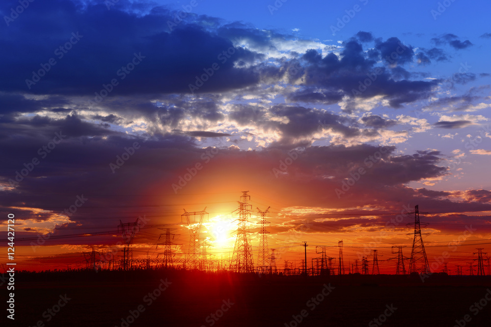 Many high voltage towers under the sunset