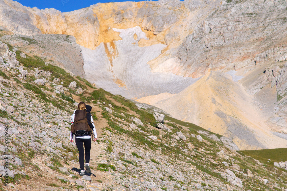 Woman Hiking with Backpack in Mountains on top with glacier snow and rocks on background Woman Hiking with Backpack in Mountains on top with glacier snow and rocks on background