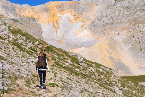 Woman Hiking with Backpack in Mountains on top with glacier snow and rocks on background